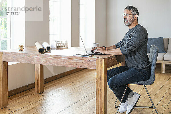 Nachdenklicher Unternehmer  der im Büro zu Hause sitzt und einen Laptop benutzt