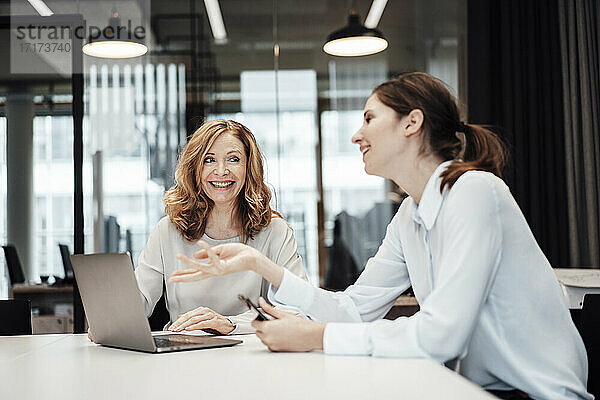 Geschäftsfrau lacht bei einer Diskussion mit einer Kollegin während einer Sitzung im Sitzungssaal