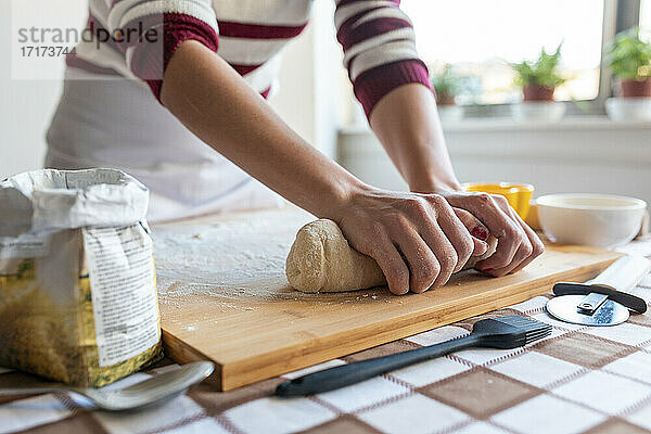 Woman kneading dough for making croissants in kitchen at home