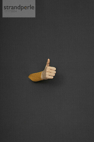 Studio shot of female hand giving thumbs up