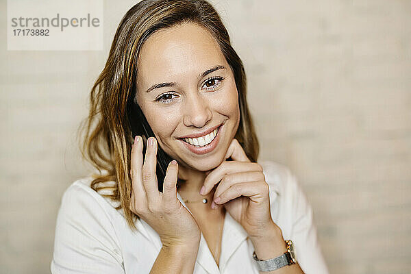 Nahaufnahme einer lächelnden weiblichen Fachkraft  die über ein Smartphone an der Wand spricht