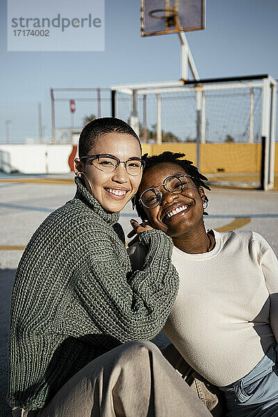 Freunde lächelnd auf dem Basketballplatz sitzend