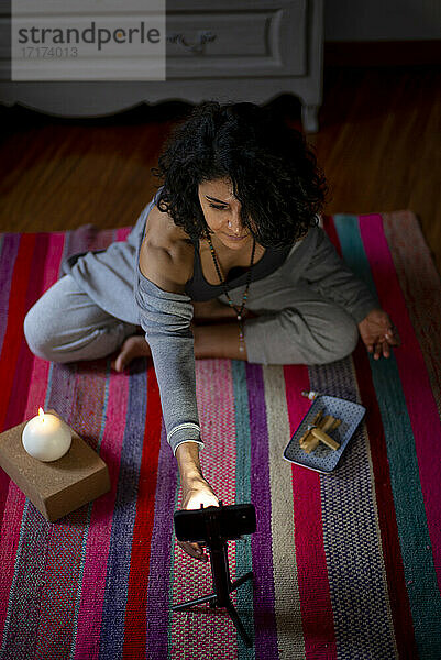 Spiritual woman adjusting mobile phone during video call at home