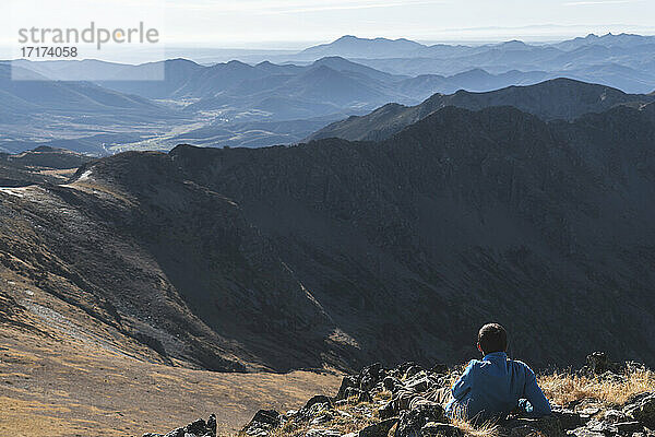 Male hiker sitting in mountain on sunny day