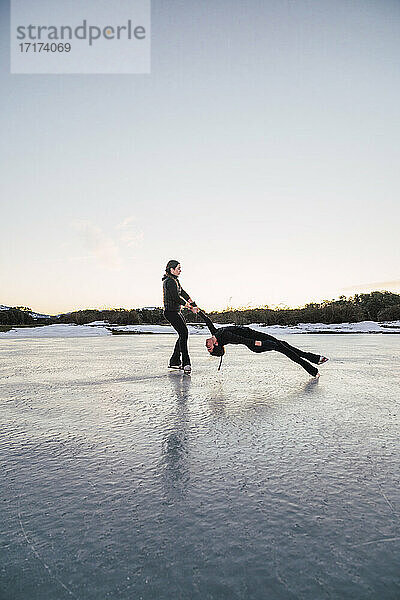 Two female figure skaters performing death spiral on frozen lake