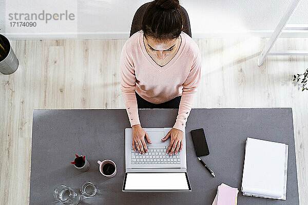 Young woman working on laptop while sitting at home office