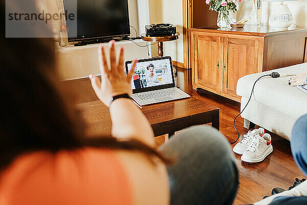 Frau bei Videoanruf mit Laptop  winkend