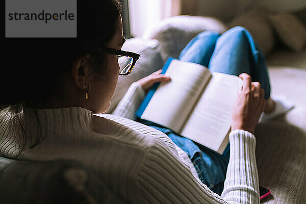 Junge Frau liest zu Hause ein Buch
