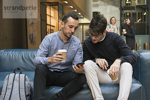Studenten in der Kaffeepause  die auf ihr Handy schauen