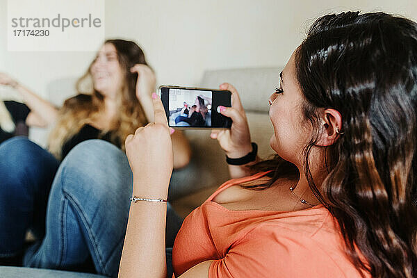 Junge Frau fotografiert Freunde mit Telefon