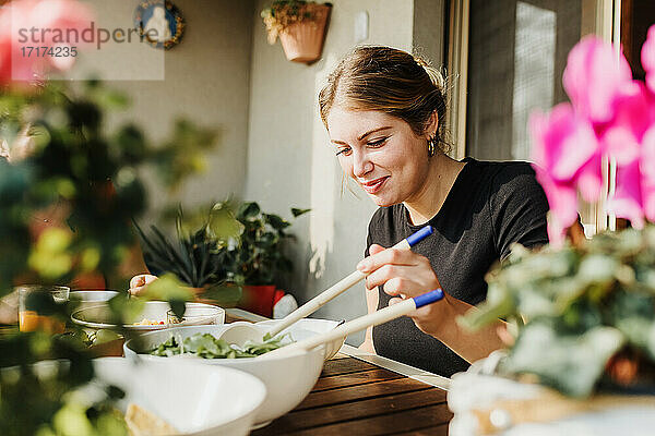Junge Frau serviert Salat