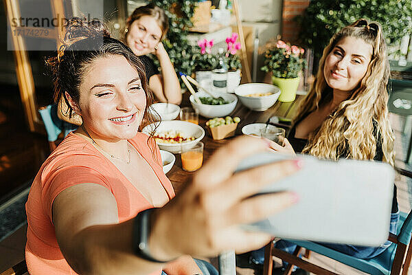 Freunde machen Selfie beim Essen auf dem Balkon