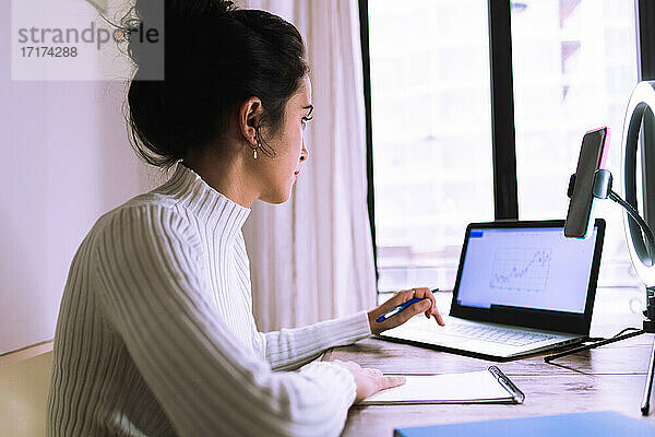 Junge Frau arbeitet von zu Hause aus mit Laptop  Telefon und Klingellicht