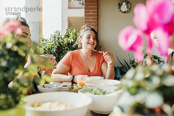 Junge Frau beim Essen auf dem Balkon
