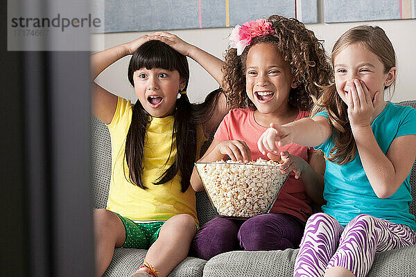 Drei Mädchen sehen fern und essen Popcorn