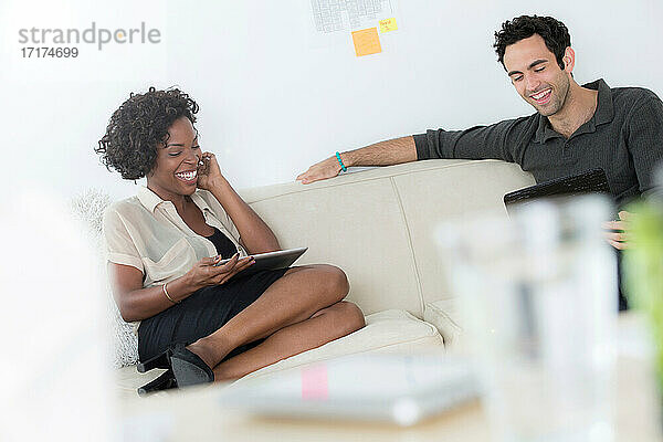 Büroangestellte auf dem Sofa mit digitalen Tablets