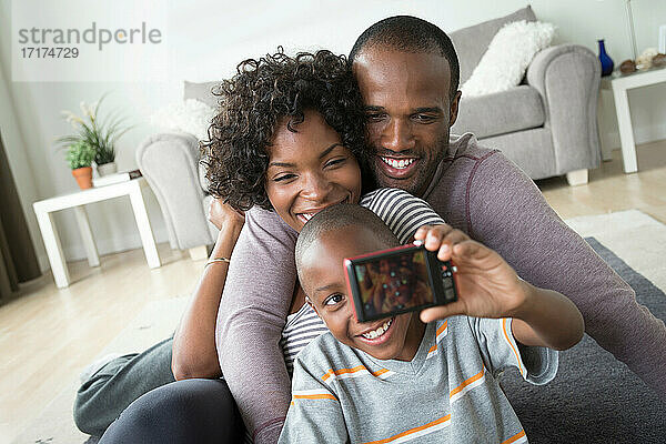 Eltern und Sohn fotografieren sich selbst mit einer Digitalkamera