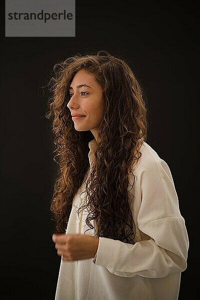 Studioaufnahme einer lächelnden jungen Frau mit langen lockigen Haaren