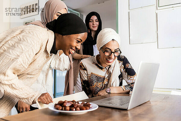 Junge muslimische Frauen bei einem Videoanruf  mit einem Teller voller Datteln
