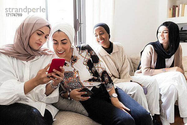 Vier junge muslimische Frauen  die auf ihr Mobiltelefon schauen