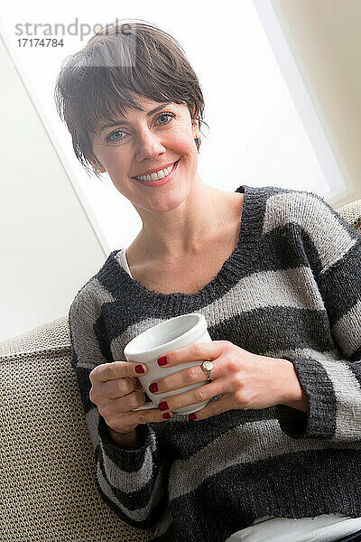 Mittlere erwachsene Frau mit Kaffee in der Hand