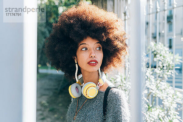 Junge Frau im Freien  schaut weg  trägt Kopfhörer