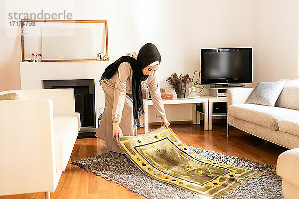 Junge muslimische Frau bereitet die Gebetsmatte vor