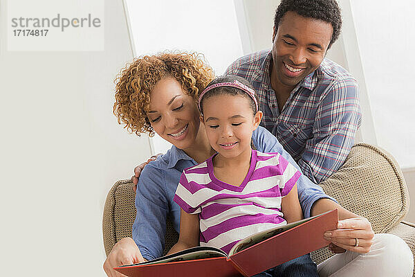 Eltern mit Tochter  die ein Buch liest