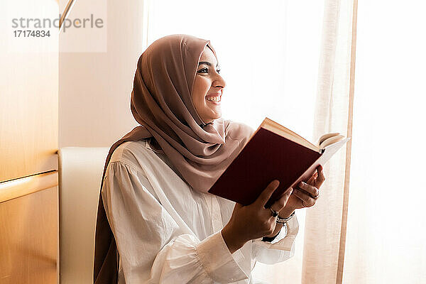 Junge muslimische Frau  lesend und lächelnd