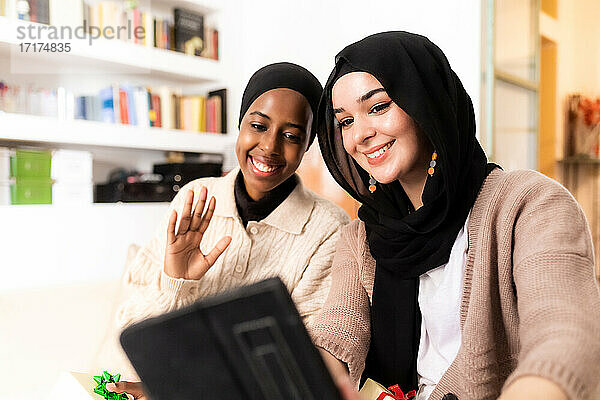 Zwei junge muslimische Frauen benutzen ein Tablet für einen Anruf