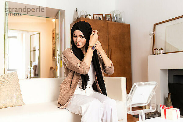 Junge muslimische Frau beim Anlegen des Hijab-Kopftuches