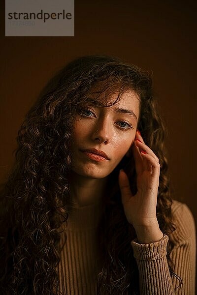 Studioporträt einer jungen Frau mit langen lockigen Haaren