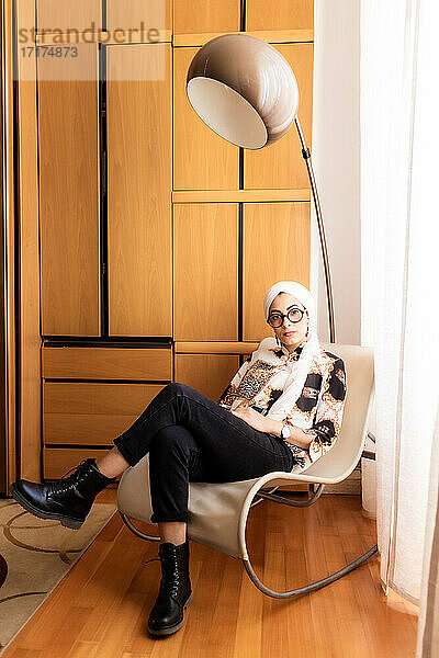 Porträt einer stilvollen jungen Frau auf einem Stuhl