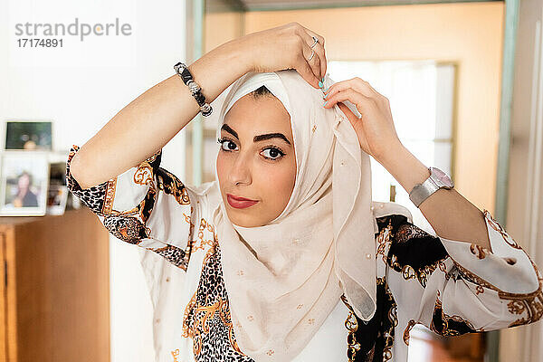 Junge muslimische Frau beim Anlegen des Hijab-Kopftuches