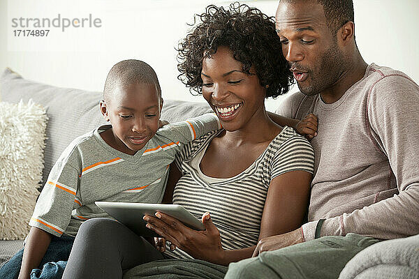 Junge mit Eltern auf dem Sofa mit digitalem Tablet