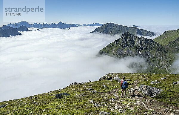 Wanderin blickt über Berglandschaft in Wolken  Blick vom Gipfel des Stornappstinden  Lofoten  Nordland  Norwegen  Europa