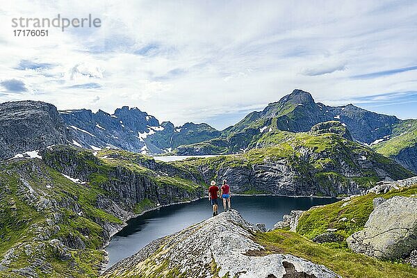 Zwei Wanderer blicken über See Tennesvatnet  Berglandschaft  Moskenesöy  Lofoten  Nordland  Norwegen  Europa
