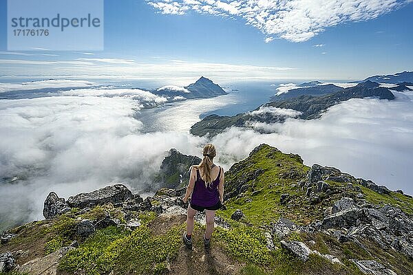 Wanderin blickt über Berglandschaft in Wolken  Blick vom Gipfel des Stornappstinden  Lofoten  Nordland  Norwegen  Europa