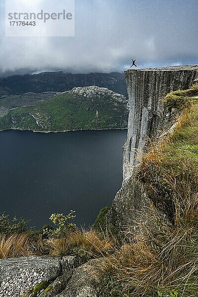 Person springt in die Luft  steile Klippe  Felskanzel Preikestolen  Lysefjord  Ryfylke  Rogaland  Norwegen  Europa