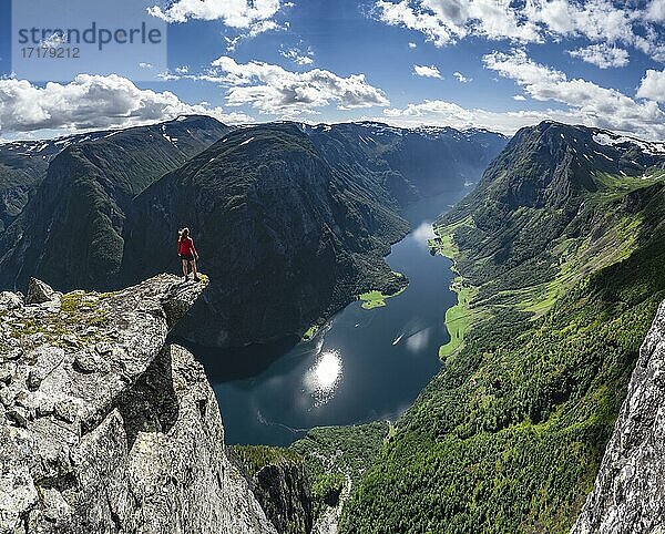 Wanderin steht auf Felszunge  Blick vom Gipfel des Breiskrednosi  Berge und Fjord  Nærøyfjord  Aurland  Norwegen  Europa