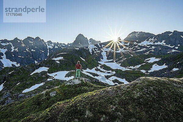 Junge Frau in den Bergen  genießt Ausblick  Berge und Schnee  Wanderung zur Trollfjord Hytta  am Trollfjord  Lofoten  Nordland  Norwegen  Europa
