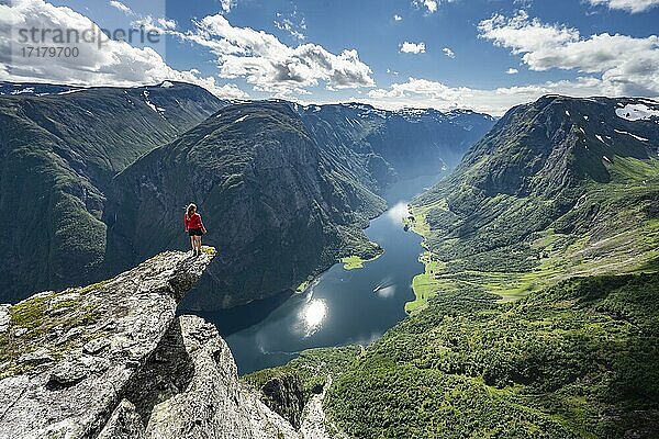 Wanderin steht auf Felszunge  Blick vom Gipfel des Breiskrednosi  Berge und Fjord  Nærøyfjord  Aurland  Norwegen  Europa