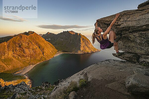 Abendstimmung  Junge Frau beim Bouldern  klettern  Gipfel des Ryten  Meer  Kvalvika Strand und Berge  Fredvang  Lofoten  Nordland  Norwegen  Europa