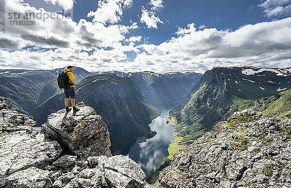 Wanderer steht auf Felsen  Blick vom Gipfel des Breiskrednosi  Berge und Fjord  Nærøyfjord  Aurland  Norwegen  Europa