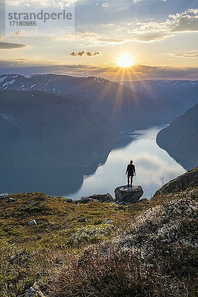 Wanderin genießt Ausblick  Sonnenuntergang am Gipfel des Berges Prest  Fjord Aurlandsfjord  Aurland  Norwegen  Europa