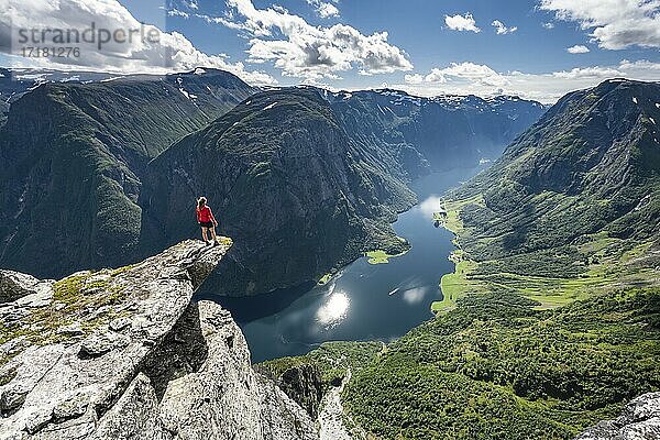 Wanderin steht auf Felszunge  Blick vom Gipfel des Breiskrednosi  Berge und Fjord  Nærøyfjord  Aurland  Norwegen  Europa