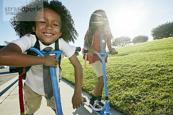 Ein 6-jähriger Junge und seine ältere Schwester auf Motorrollern auf einem Weg