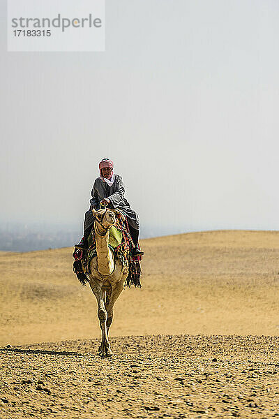 Mann reitet auf einem Kamel in der Wüste außerhalb von Kairo