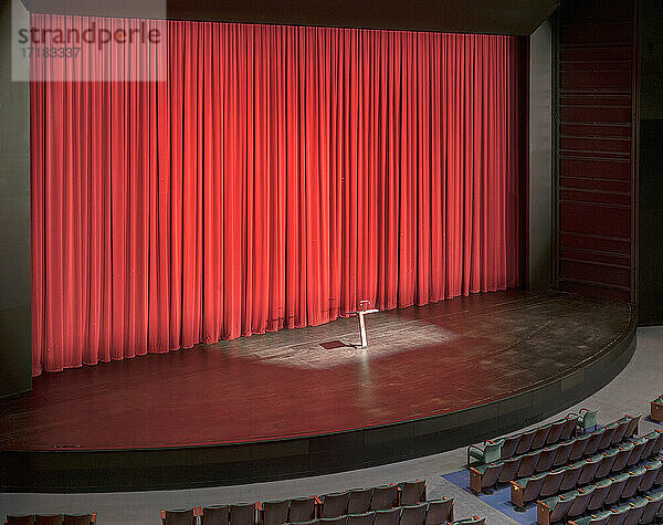 Bühne mit roten Vorhängen in einem leeren Zuschauerraum.