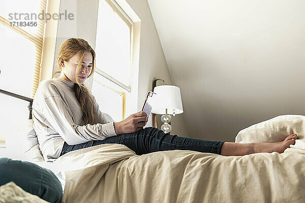 Teenager-Mädchen liegt im Bett und benutzt ihr Smartphone